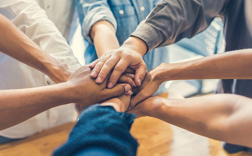 who-we-are-community-kerioth 8 arms of people outstretched joining hands in a show of solidarity
